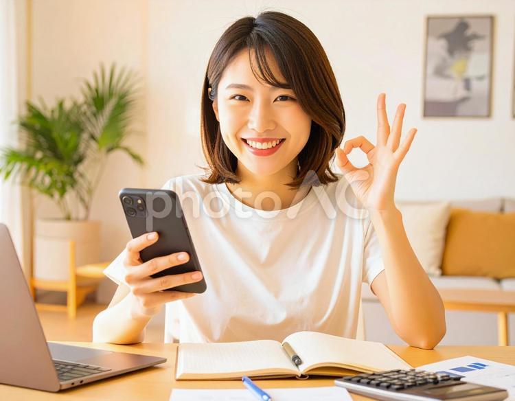 家計がうまくいきスマホ片手に微笑む女性 パソコン,家計簿,節約の写真素材