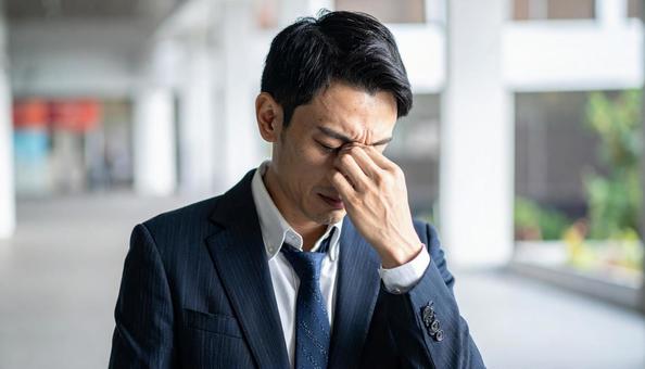 目を手で押さえて苦しむ日本人ビジネスマン 目を手で押さえて苦しむ日本人ビジネスマンの写真