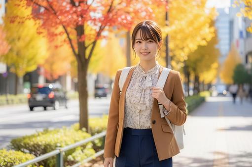 紅葉を背景にストリートを歩く女性会社員 紅葉を背景にストリートを歩く女性会社員の写真