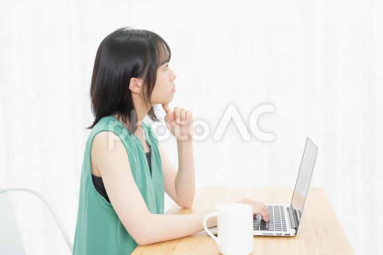 肘をついて考え事をしている若い女性 ノートパソコン,パソコン,女性の写真素材
