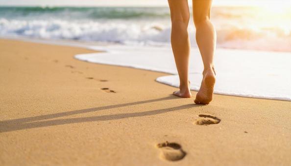 波打ち際の砂浜に足あとと女性の白い足 波打ち際の砂浜に足あとと女性の白い足の写真