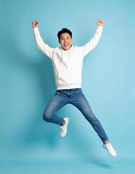 ガッツポーズでジャンプする若い男性 ガッツポーズでジャンプする若い男性の写真