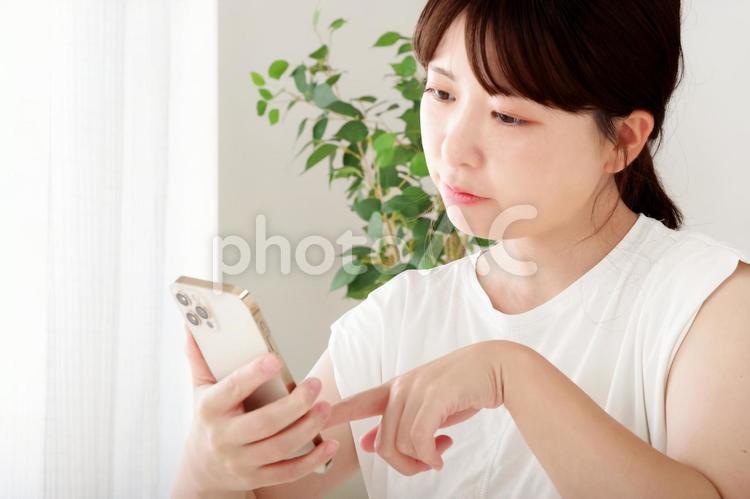 曇った表情でスマホを見つめる若い女性 エゴサーチ,不機嫌,喧嘩の写真素材