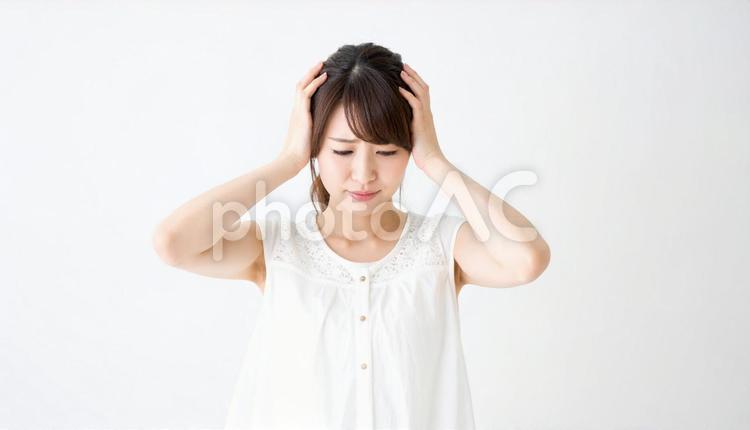 頭を押さえて辛そうな表情をする女性 人物,困惑,ネガティブの写真素材