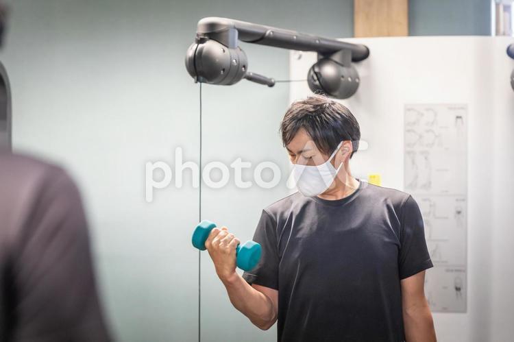 スポーツジムでダンベルを使う男性（マスク） ダンベル,負荷,筋トレの写真素材