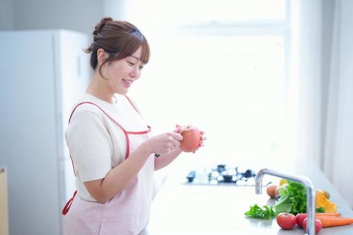 笑顔でリンゴの皮むきをする女性 女性,リンゴ,皮むきの写真素材