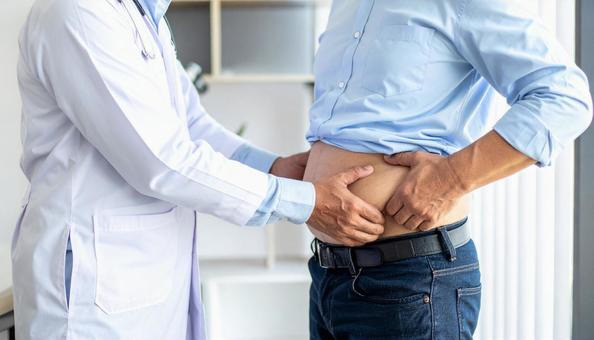 メタボリックなお腹に手を触れる男性 メタボリックなお腹に手を触れる男性の写真