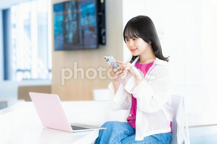 スマホを見る笑顔の女性 スマホ,若い女性,笑顔の写真素材