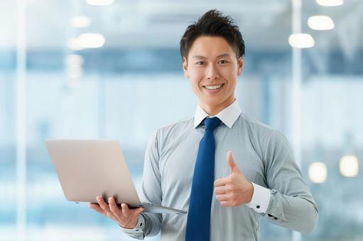 パソコンを持っていいねのポーズをする男性 男性,パソコン,ビジネスの写真素材