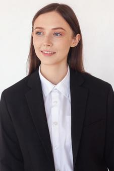 横を見るスーツのロングヘア女性の写真