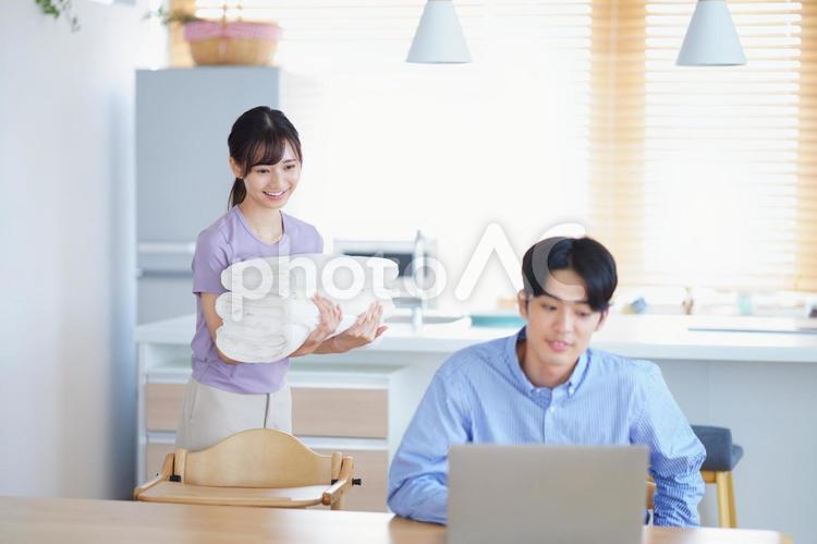 男性の方を見るタオルを運ぶ笑顔の女性 男女,ノートパソコン,テレワークの写真素材
