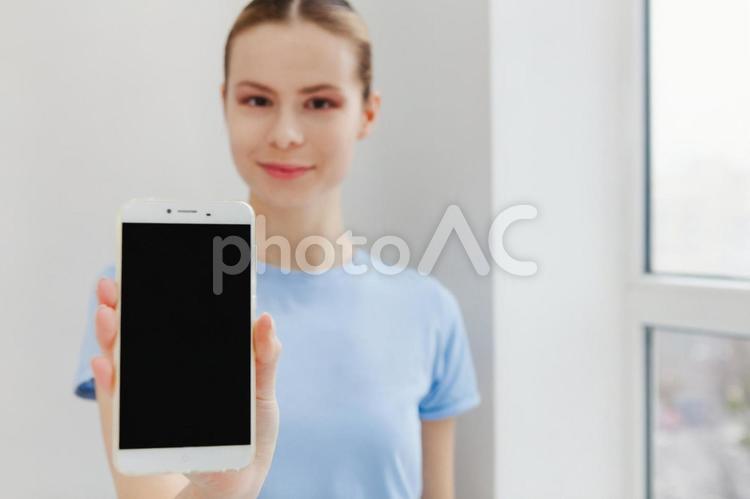 微笑みスマホの画面を見せる女性 女性,スマートフォン,画面の写真素材