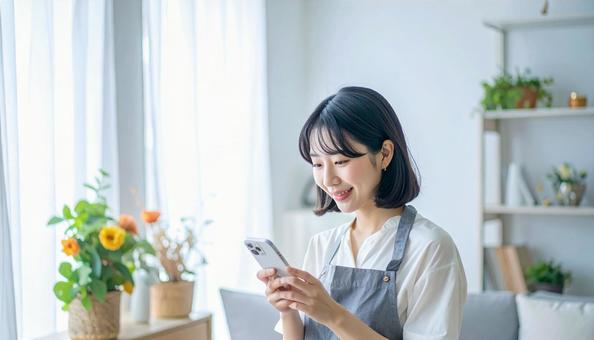 スマホでポイ活する笑顔の女性 スマホでポイ活する笑顔の女性の写真