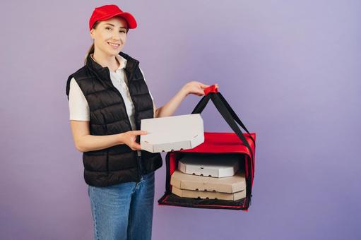 保温ピザバッグからピザ箱出して持つ女性配達員 配達,フードデリバリー,デリバリーの写真素材