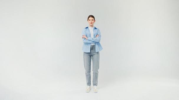 腕組みをして立つジーンズの女性 腕組みをして立つジーンズの女性の写真