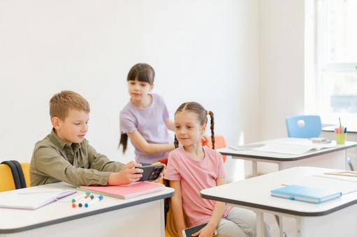 男の子の携帯を見る女の子たち 男の子,女の子,子どもの写真素材