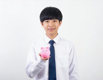 ブタの貯金箱をもつ男の子・男子生徒の写真
