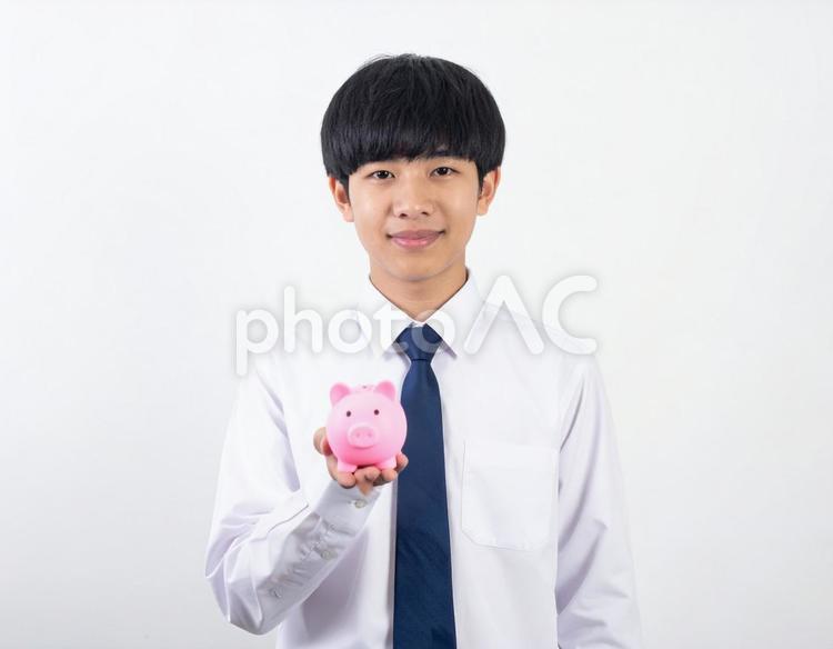 ブタの貯金箱をもつ男の子・男子生徒 貯金箱,男の子,お金の写真素材