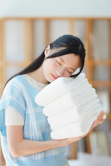 畳んで重ねたタオルを持つ目を瞑った女性 女性,日本人,タオルの写真素材