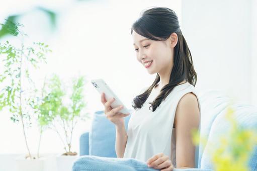 明るい部屋でスマートフォンを操作する女性 明るい部屋でスマートフォンを操作する女性 女性,スマホ,snsの写真素材