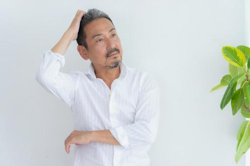 リビングでヘアケアをするミドルの男性 リビングでヘアケアをするミドルの男性 ヘアケア,育毛,ヘアセットの写真素材