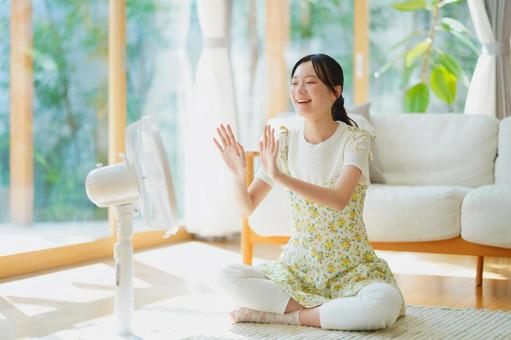 扇風機に手を向け笑顔の女性 女性,扇風機,涼しいの写真素材