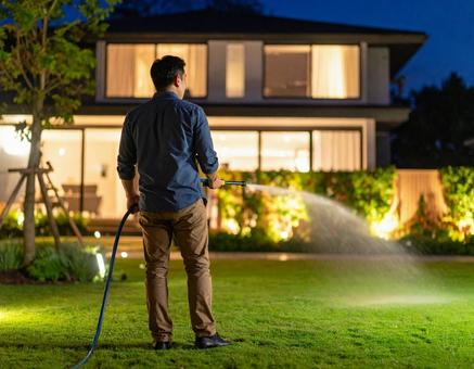 芝生に水をまく男性の後ろ姿 芝生に水をまく男性の後ろ姿の写真