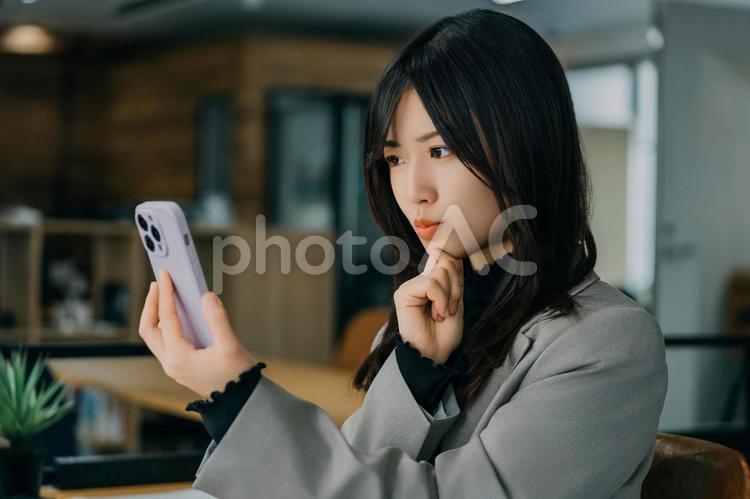 スマホを見て考える女性・ビジネスウーマン 女性,困る,考えるの写真素材