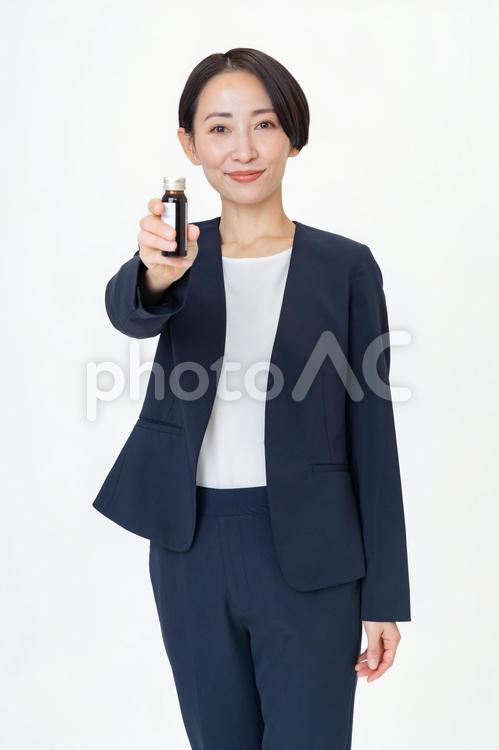 栄養ドリンクを持つスーツを着た女性 栄養ドリンク,ビジネスウーマン,元気の写真素材