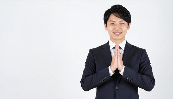 両手をあわせてお願いしているビジネスマン 両手をあわせてお願いしているビジネスマンの写真