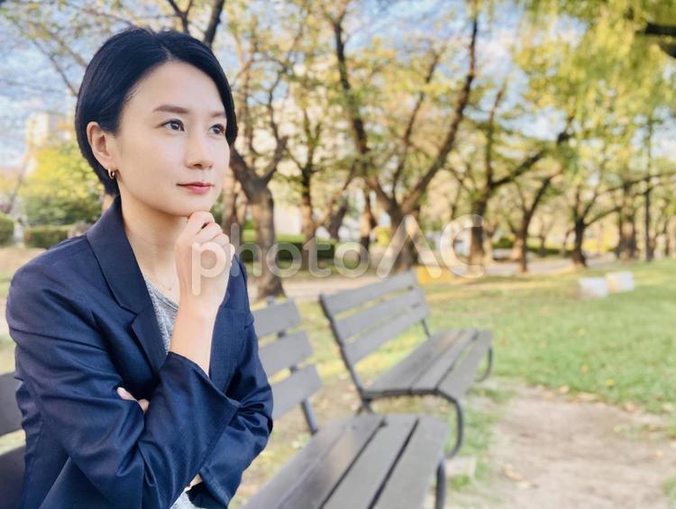 公園のベンチで目標を考えるスーツの女性 女性,笑顔,スーツの写真素材