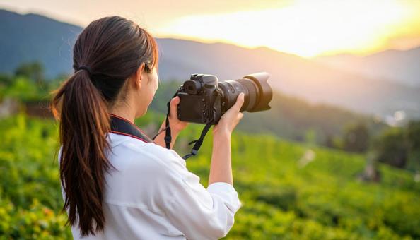 一眼レフを首から下げ手に取る女性 一眼レフを首から下げ手に取る女性の写真