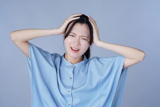 頭を抱えた青い服の女性 女性,頭を抱える,困るの写真素材