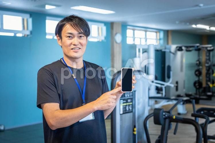 スポーツジムで働くスポーツトレーナー（スマホ） スポーツジム,スマートフォン,スマホの写真素材