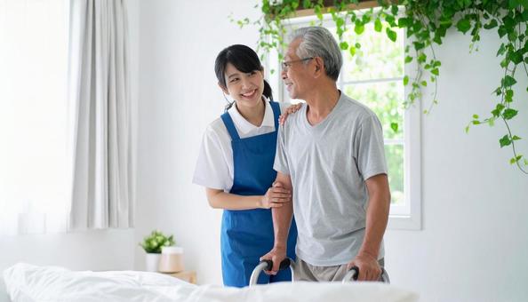 シニア男性の起き上りを補助するヘルパーの写真