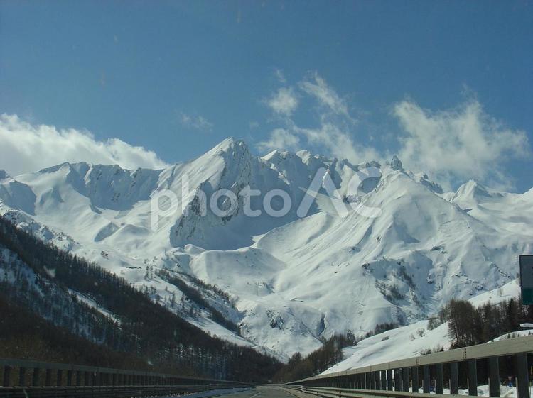 白いアルプスの中を、車で走る アルプス,雪山,道路の写真素材