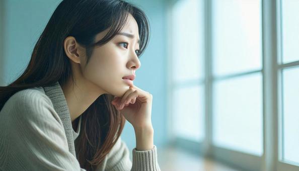 困った顔で手を顎に当てる若い女性 困った顔で手を顎に当てる若い女性の写真