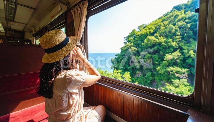 車窓から夏の海を見つめる日本人女性乗客 窓際,車窓,ノスタルジックの写真素材