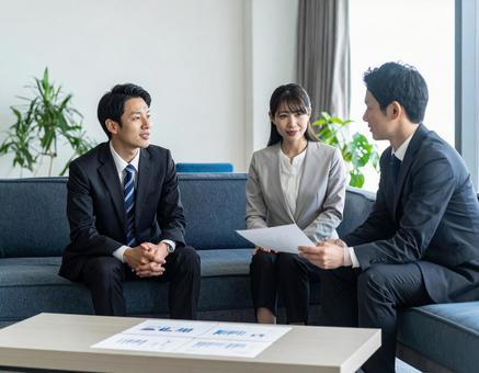 応接室でお客様に資料を説明する上司と部下の写真