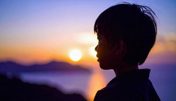 夕焼けの空を見つめる日本人の少年 夕焼けの空を見つめる日本人の少年の写真