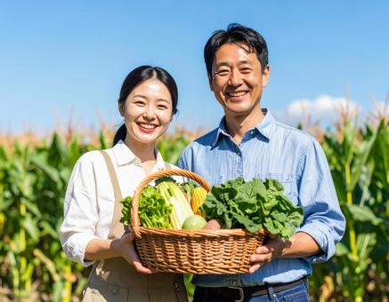収穫した野菜を手に笑顔の農家夫婦 収穫した野菜を手に笑顔の農家夫婦の写真