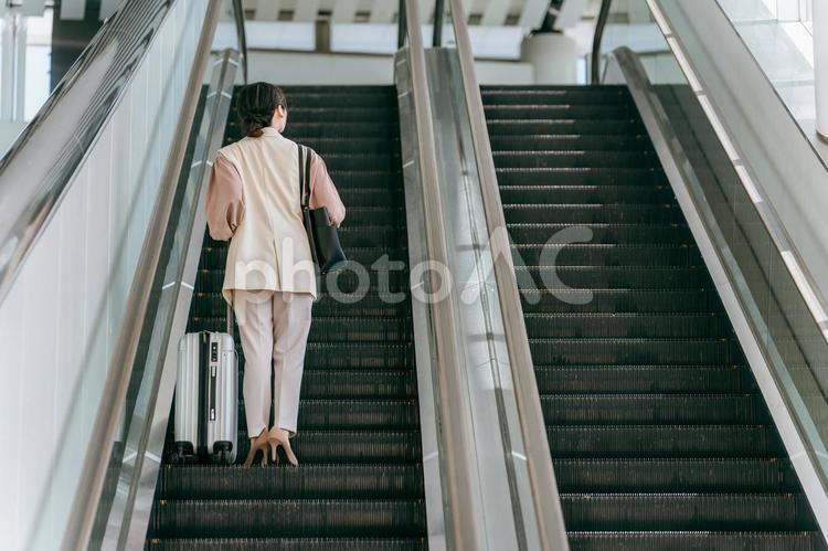 駅のエスカレーターを昇るビジネスウーマン 出張,海外出張,ビジネスウーマンの写真素材
