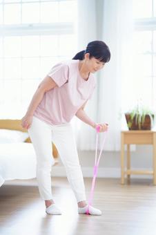 チューブを使って運動に取り組む中年女性 チューブを使って運動に取り組む中年女性 主婦,シニア,立ち姿の写真素材