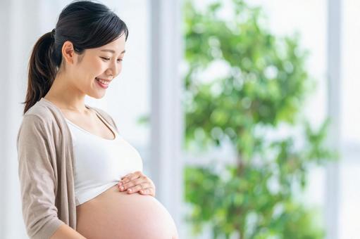 お腹をさすりながら笑顔の妊婦 お腹をさすりながら笑顔の妊婦の写真