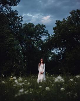 夕暮れの草原に佇む神秘的な女性 夕暮れの草原に佇む神秘的な女性の写真