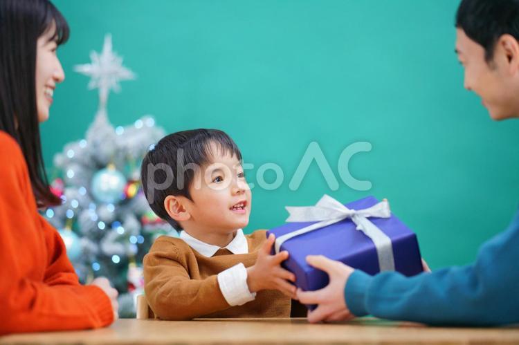 男性が渡す渡すプレゼントをもらう男の子と後ろに女性 男性,男の子,家族の写真素材