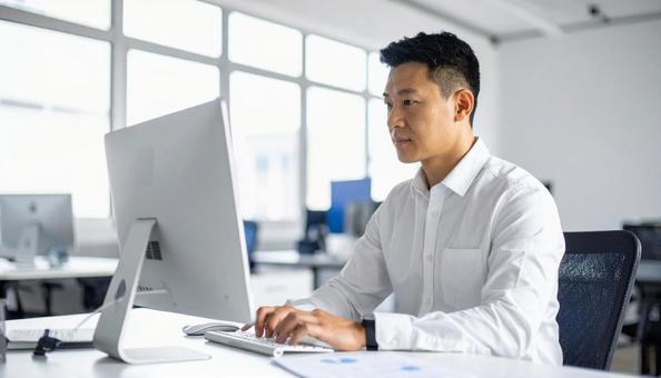 パソコンで仕事する白い服装の男性会社員 パソコンで仕事する白い服装の男性会社員の写真