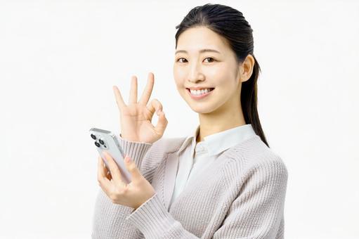 スマートフォンを持ちOKサインする女性 スマートフォンを持ちOKサインする女性 スマホ,メール,女性の写真素材