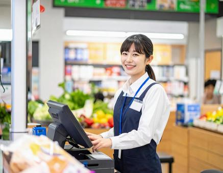 スーパーで笑顔でレジ業務をする女性店員 スーパーで笑顔でレジ業務をする女性店員の写真
