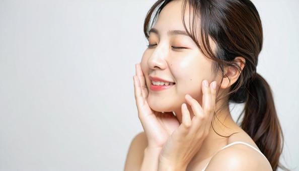 ほほをさわり満足して目をつむる若い女性 ほほをさわり満足して目をつむる若い女性の写真